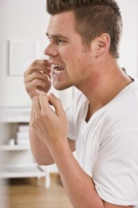 Man flossing his teeth as a preventiative form of gum disease treatment