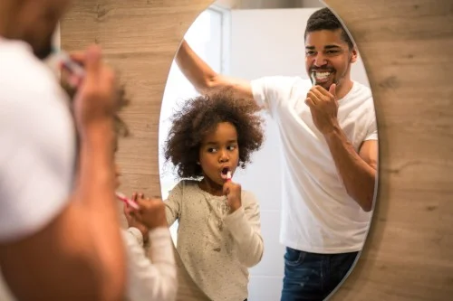 dad watches daughter brush teeth