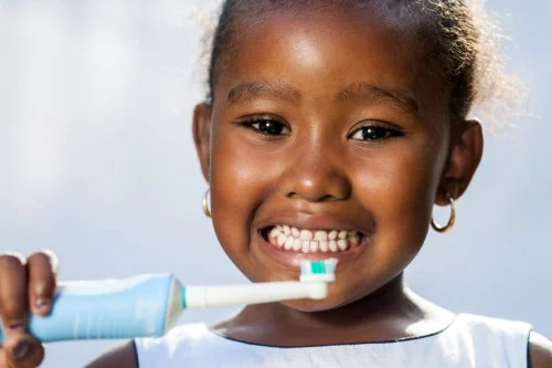 little girl using electric toothbrush